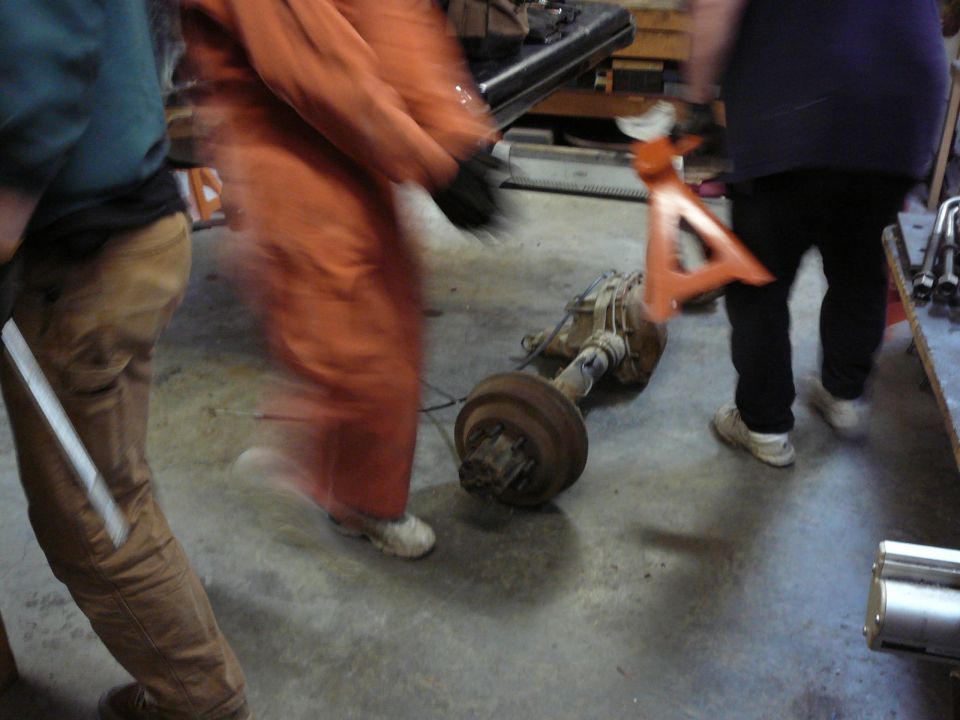 People working on a vehicle axle assembly in a garage