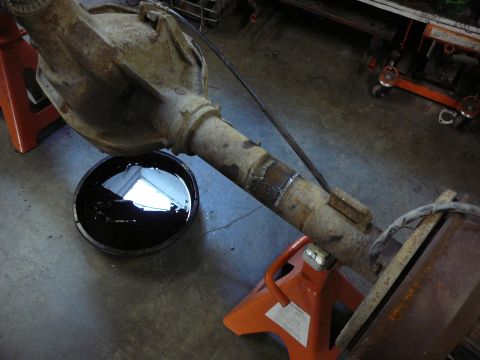 1991 Ford Bronco - Rear axle assembly supported by jack stands, with a drain pan collecting fluid.