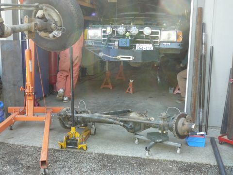 1991 Ford Bronco - A green Ford Bronco is undergoing maintenance in a garage, supported by jack stands.