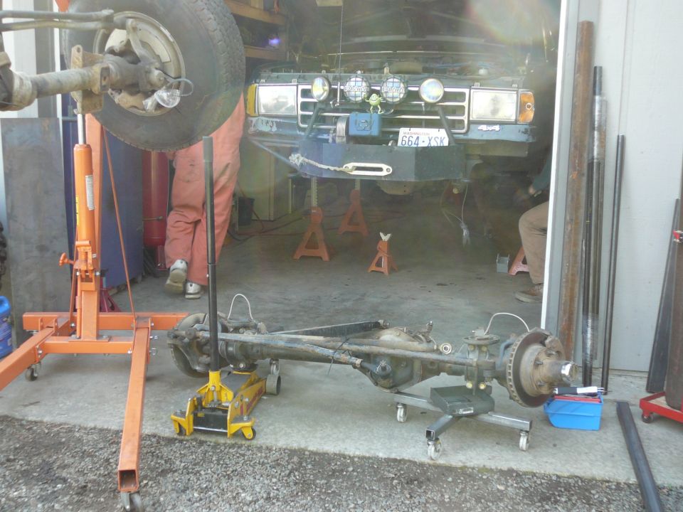 Green Ford Bronco with aftermarket bumper and winch, on jack stands