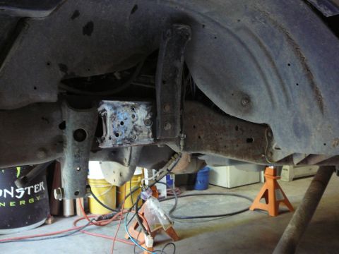 1991 Ford Bronco - Close-up of modified vehicle frame and suspension parts, with visible "Monster Energy" branding on a nearby object.
