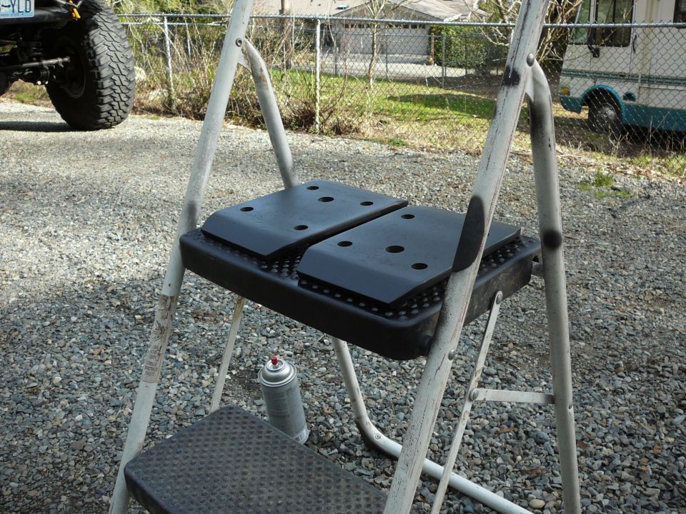 Step ladder with two black plastic platforms and a spray can on the ground