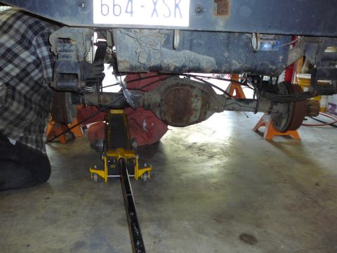 1991 Ford Bronco - Underneath view of a vehicle's rear axle and suspension system being worked on.