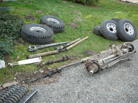 1991 Ford Bronco - Various automotive parts, including tires and suspension components, are scattered on the ground.