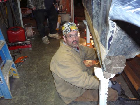1991 Ford Bronco - A man works on the underside of a vehicle in a garage setting.