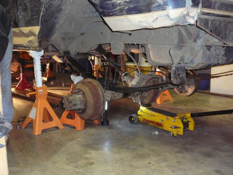 1991 Ford Bronco - The rear suspension and axle assembly of a vehicle are elevated on jack stands for maintenance.