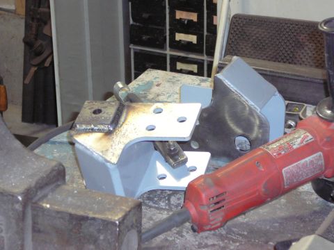 1991 Ford Bronco - Custom metal brackets are shown on a workbench next to a red angle grinder, possibly for a vehicle modification.