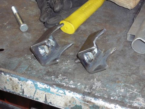 1991 Ford Bronco - Custom metal brackets, likely for a vehicle modification, sit on a workbench with tools.