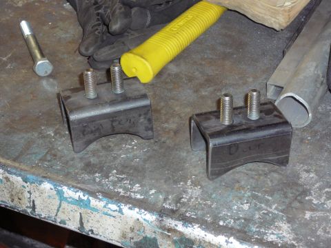 1991 Ford Bronco - Metal brackets with bolts are on a workbench, suggesting automotive parts or modifications.