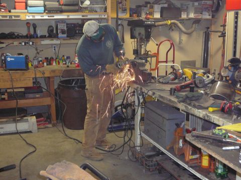 1991 Ford Bronco - A person is using an angle grinder on metal in a workshop, creating a shower of sparks.