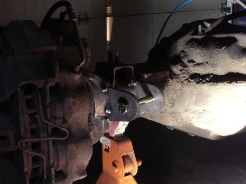 1991 Ford Bronco - Close-up view of a custom suspension modification on a vehicle's axle, held in place by a jack stand.