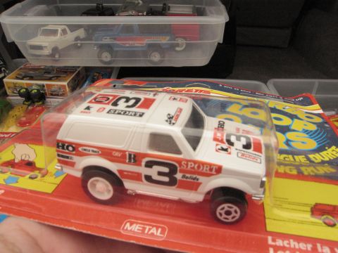 1986 Ford Bronco - Diecast toy Bronco with racing graphics is displayed in its original packaging, alongside other toys.