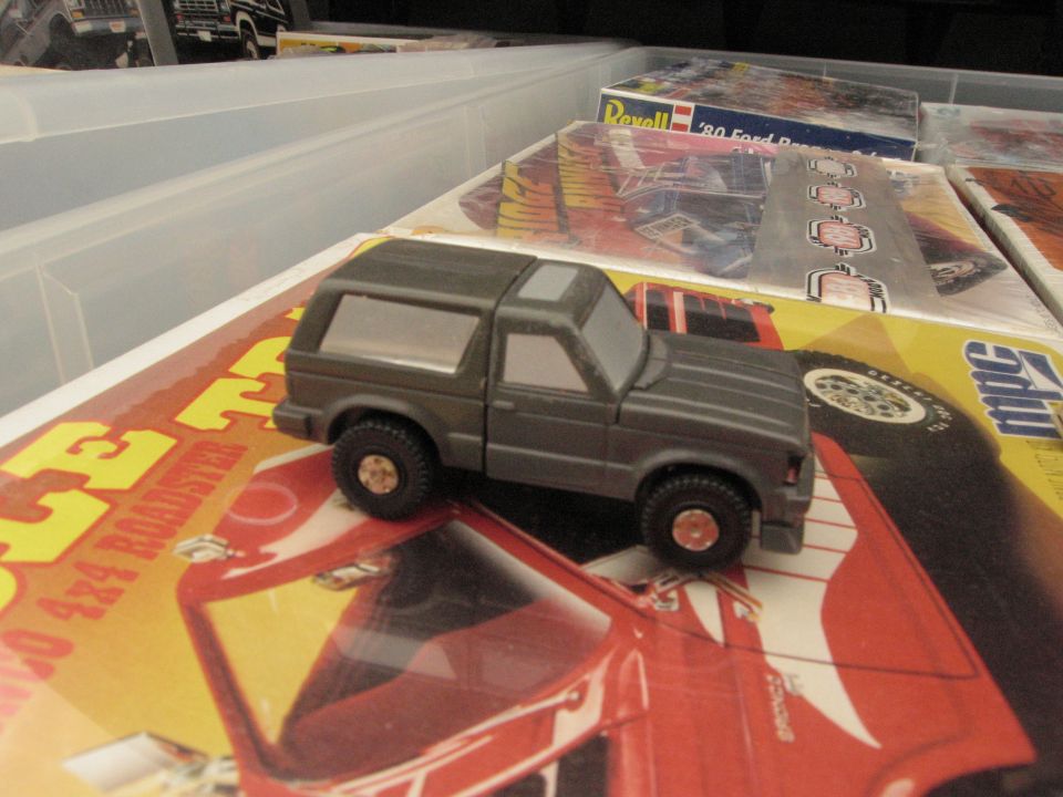 Gray toy model of a 1986 Ford Bronco sitting on model kit boxes