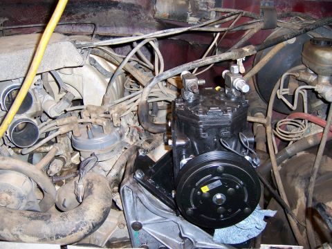 1991 Ford Bronco - Close-up view of a black air conditioning compressor installed in a vehicle's engine bay.