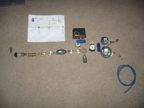 1989 Ford Bronco - A collection of air compressor components and a schematic diagram are displayed on a carpeted surface.