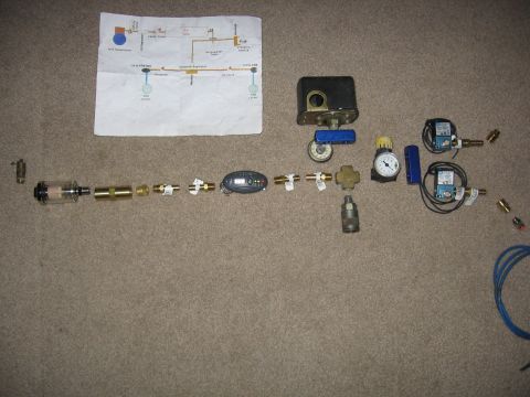 1989 Ford Bronco - Disassembled air compressor components and a schematic diagram are spread across a carpeted floor.
