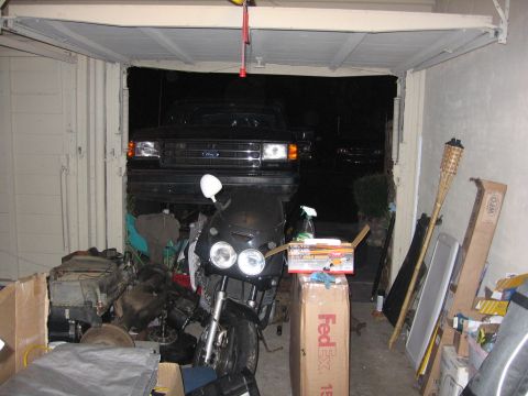 1989 Ford Bronco - A black Ford truck is parked in a garage filled with various items.