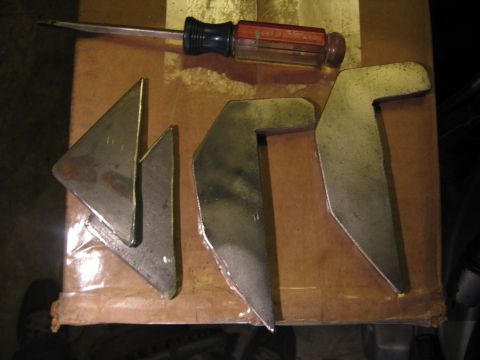1989 Ford Bronco - Metal brackets and a screwdriver are laid out on a cardboard box.