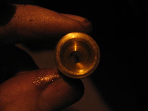 1989 Ford Bronco - A close-up view of a small brass fitting held by a finger against a dark background.