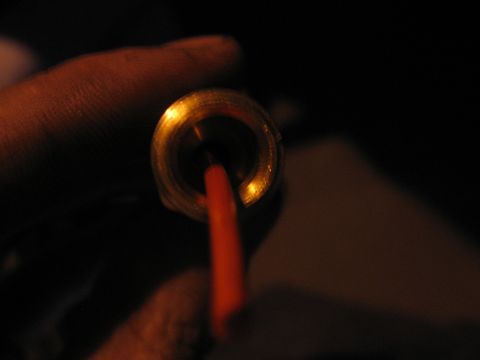 1989 Ford Bronco - Close-up view of a brass fitting with an orange wire inserted into it.