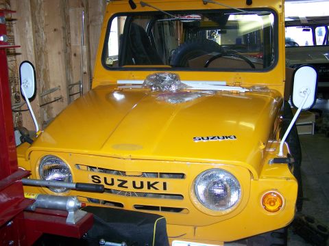 1988 Suzuki Samurai - A yellow Suzuki Samurai is parked indoors, showing its front grille and hood with prominent badging.