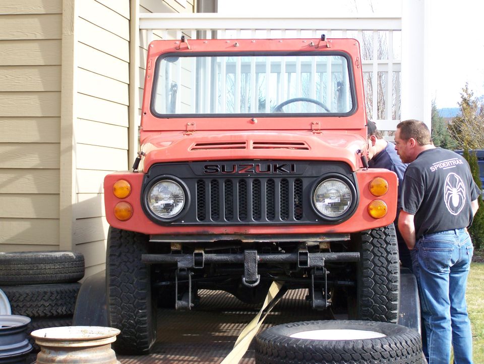 Front view of a red Suzuki off-road mini truck on lift