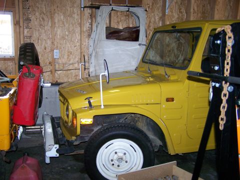 1988 Suzuki Samurai - A yellow 1988 Suzuki Samurai is parked inside a garage, with a spare tire and gas cans visible.