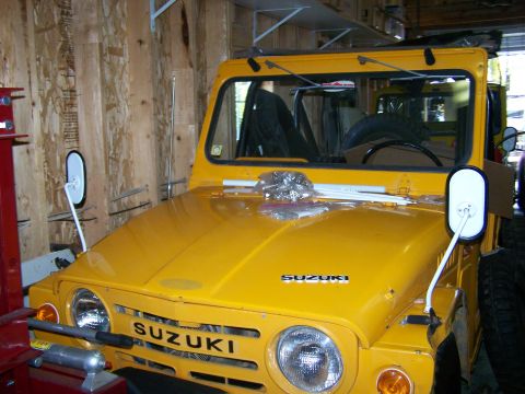 1988 Suzuki Samurai - This yellow Suzuki Samurai is parked indoors, with its front grille and hood clearly visible.