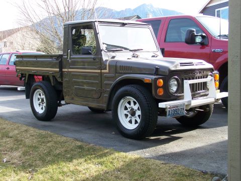 1988 Suzuki Samurai - A brown Suzuki pickup truck is parked in a driveway next to a red Ford F-250.
