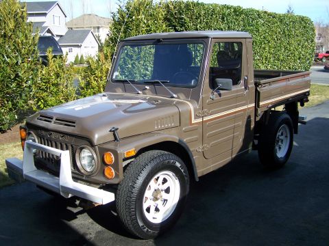 1988 Suzuki Samurai - Brown 1988 Suzuki Samurai pickup truck parked in a driveway with houses in the background.