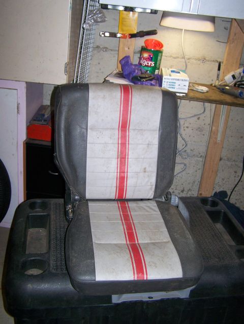 1988 Suzuki Samurai - A close-up of a vehicle seat with red and white stripes, placed on a black console unit.