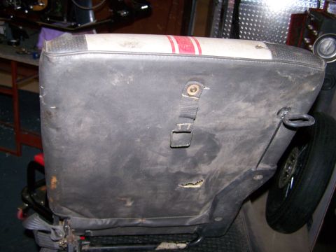 1988 Suzuki Samurai - A worn car seat with visible damage and a spare tire in the background.