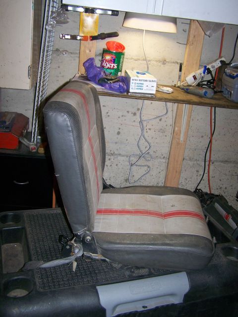 1988 Suzuki Samurai - A single vehicle seat with a worn fabric pattern is shown in a cluttered garage or workshop area.