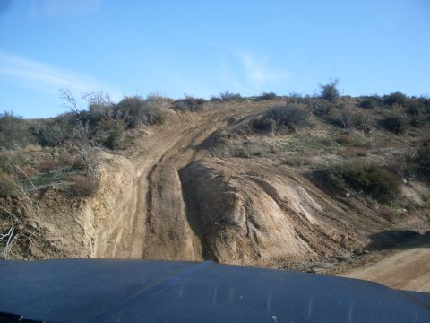 1979 Ford Bronco - Tire tracks mark an off-road trail climbing a dry, scrub-covered hillside.
