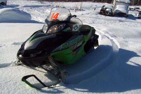 2004 Arctic Cat F-7 Firecat - A snowmobile sits in a snowy area with trucks in the background.