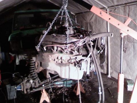 1979 Ford Bronco - Engine removed from a vehicle for rebuild, suspended by a chain hoist.