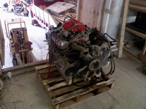 1979 Ford Bronco - An engine assembly is displayed on a pallet, with a forklift and storage shelves in the background.