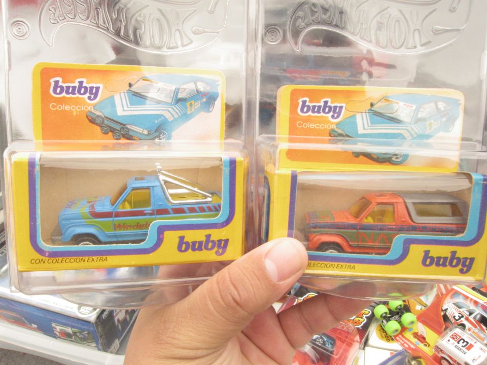 Two toy trucks in Buby packaging, one blue and one orange