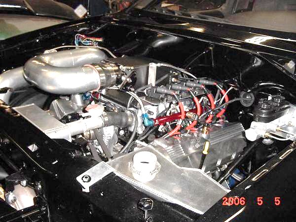 Engine bay with large intake pipes, custom wiring, and aluminum components. Date stamp reads 2006 5 5