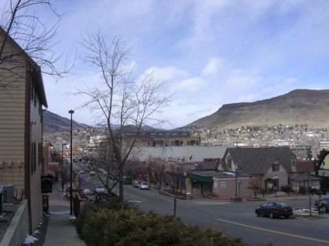 1996 Ford Bronco - A town street scene with buildings, cars, and a mountain range under a cloudy sky.