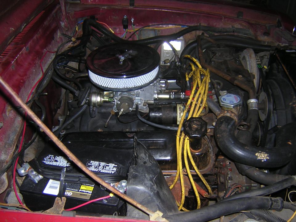 Engine bay with chrome air cleaner, yellow plug wires, black valve covers, and Diehard battery in a red car