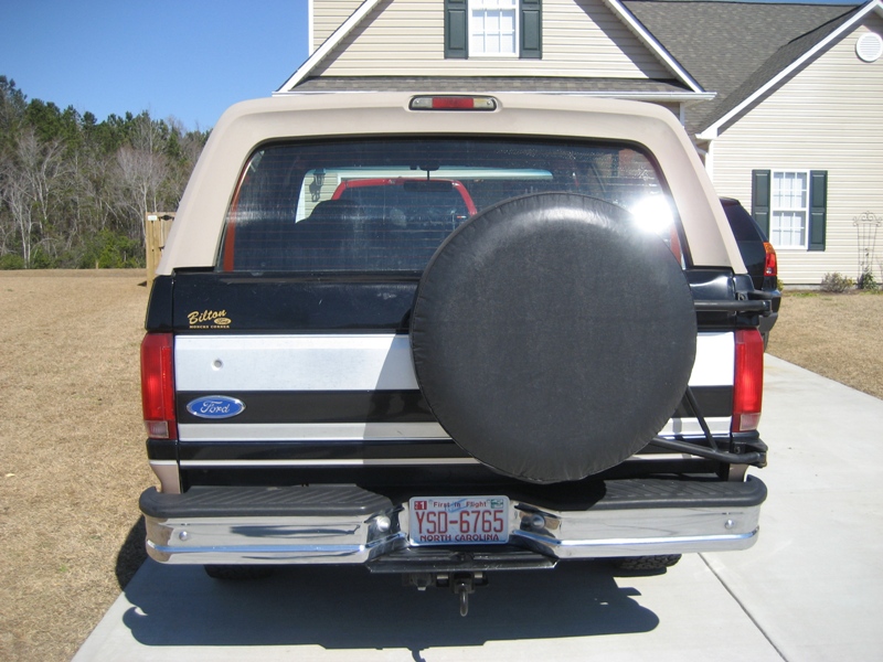 Rear view of black Ford Bronco with tire cover and NC plate