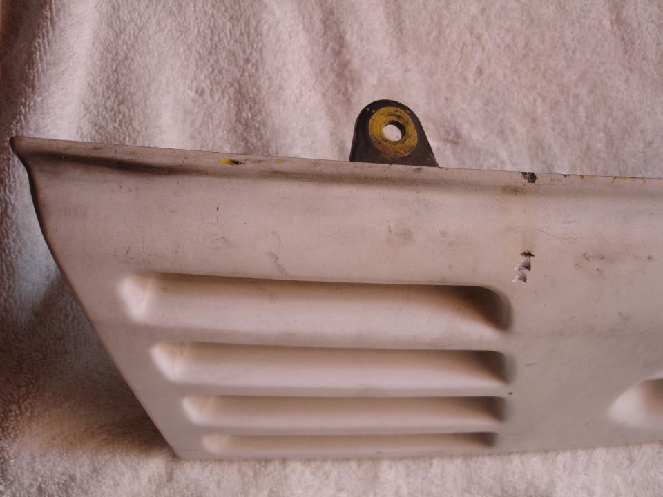 White car part with louvers and a metal mounting bracket.