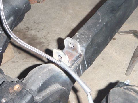 1996 Ford Bronco - A close-up view shows a custom metal bracket welded to a black metal frame component, with a braided metal hose attached to it. The bracket…