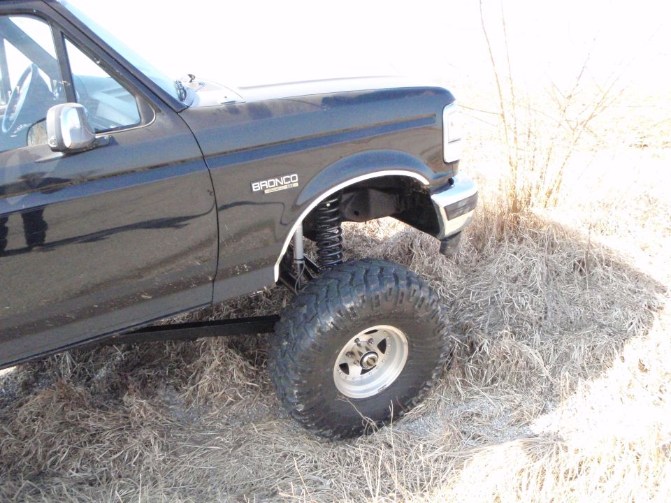 Black lifted Ford Bronco with large tires, side view.