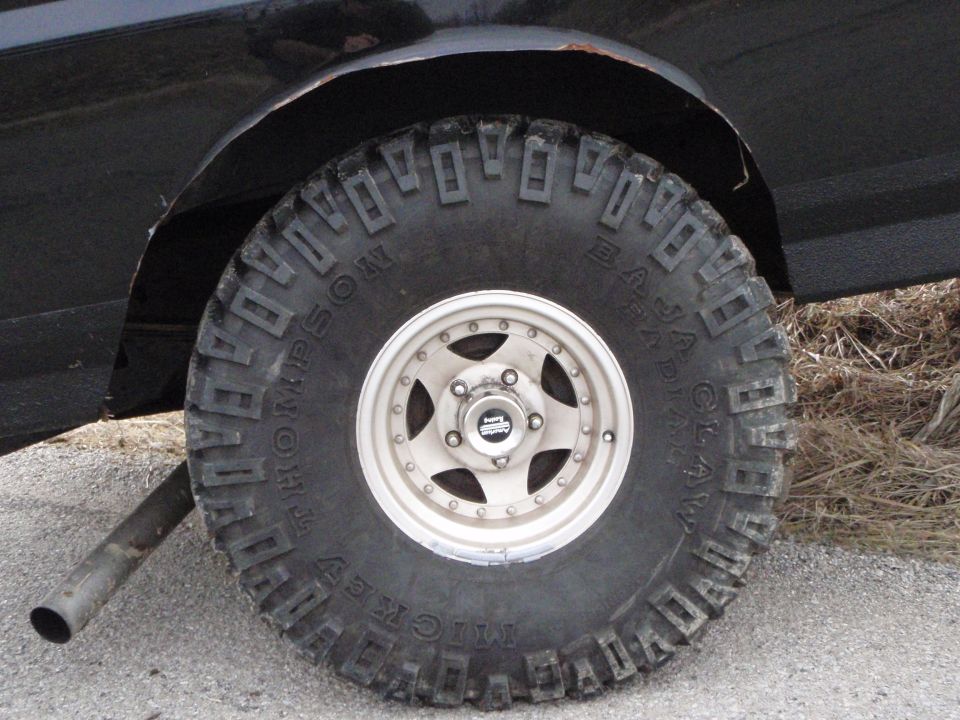 Close-up of a Mickey Thompson Baja Claw radial off-road tire on a black vehicle.