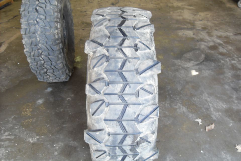 Two off-road tires on a wet concrete floor.