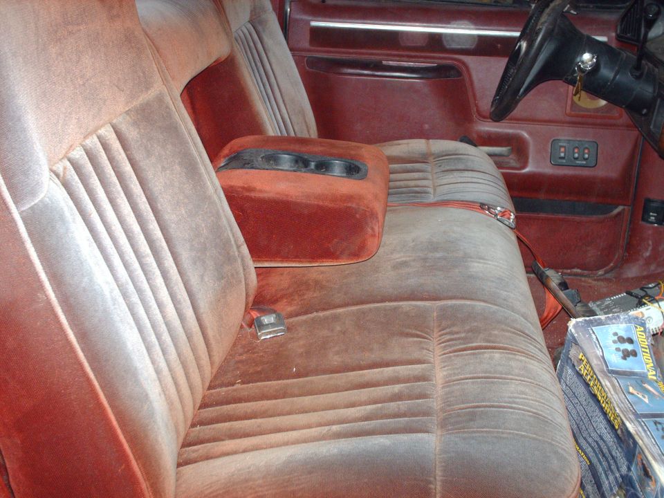 Dusty reddish-brown velour bench seat interior with center console and steering wheel.