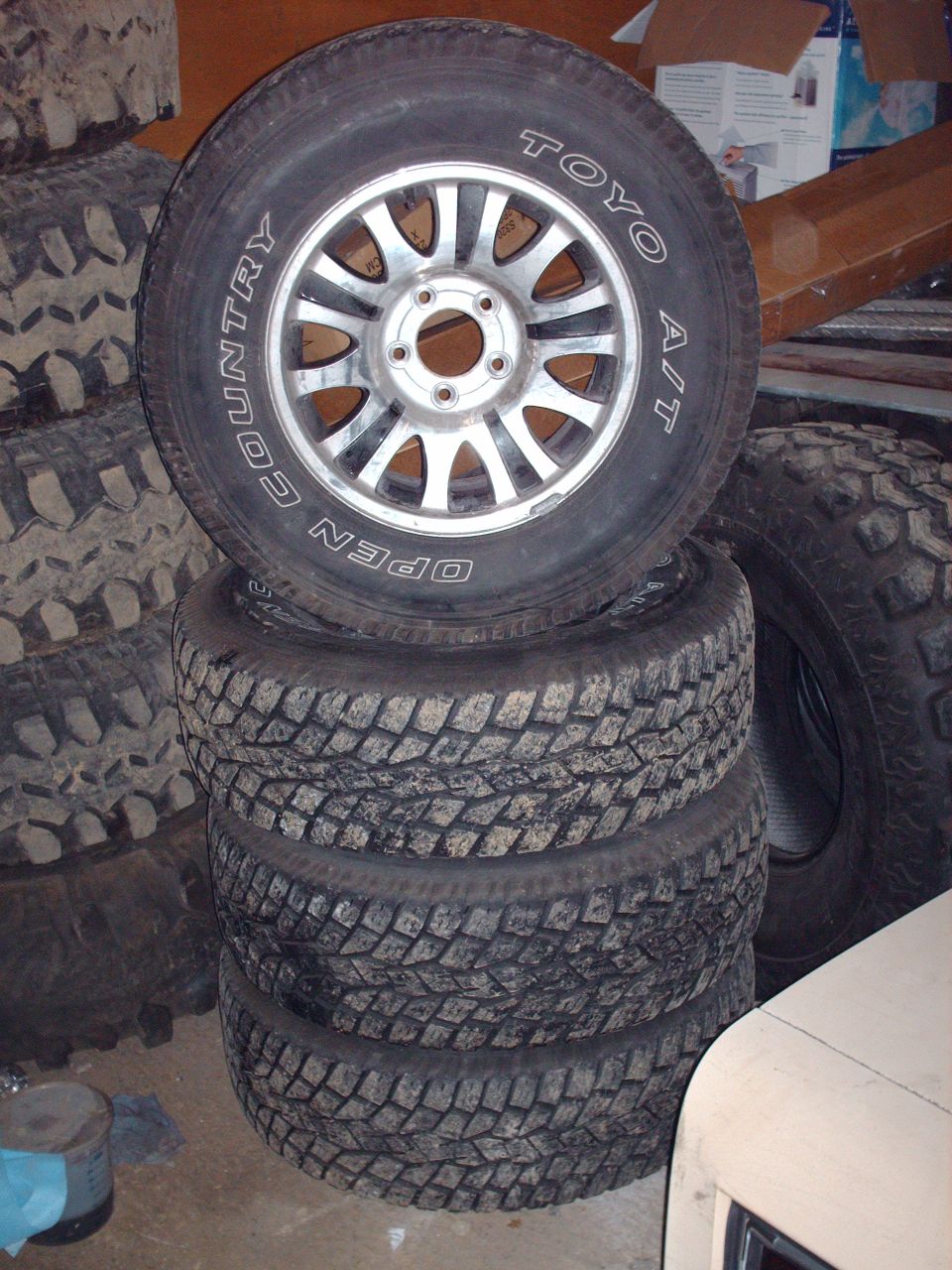 Stack of four off-road tires, top tire has chrome rim and TOYO lettering.