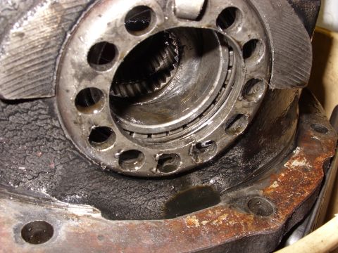 1988 Ford Bronco - A close-up view of a heavily used and greasy automotive differential housing, showing a bearing and gears within. The metal is worn and rus…